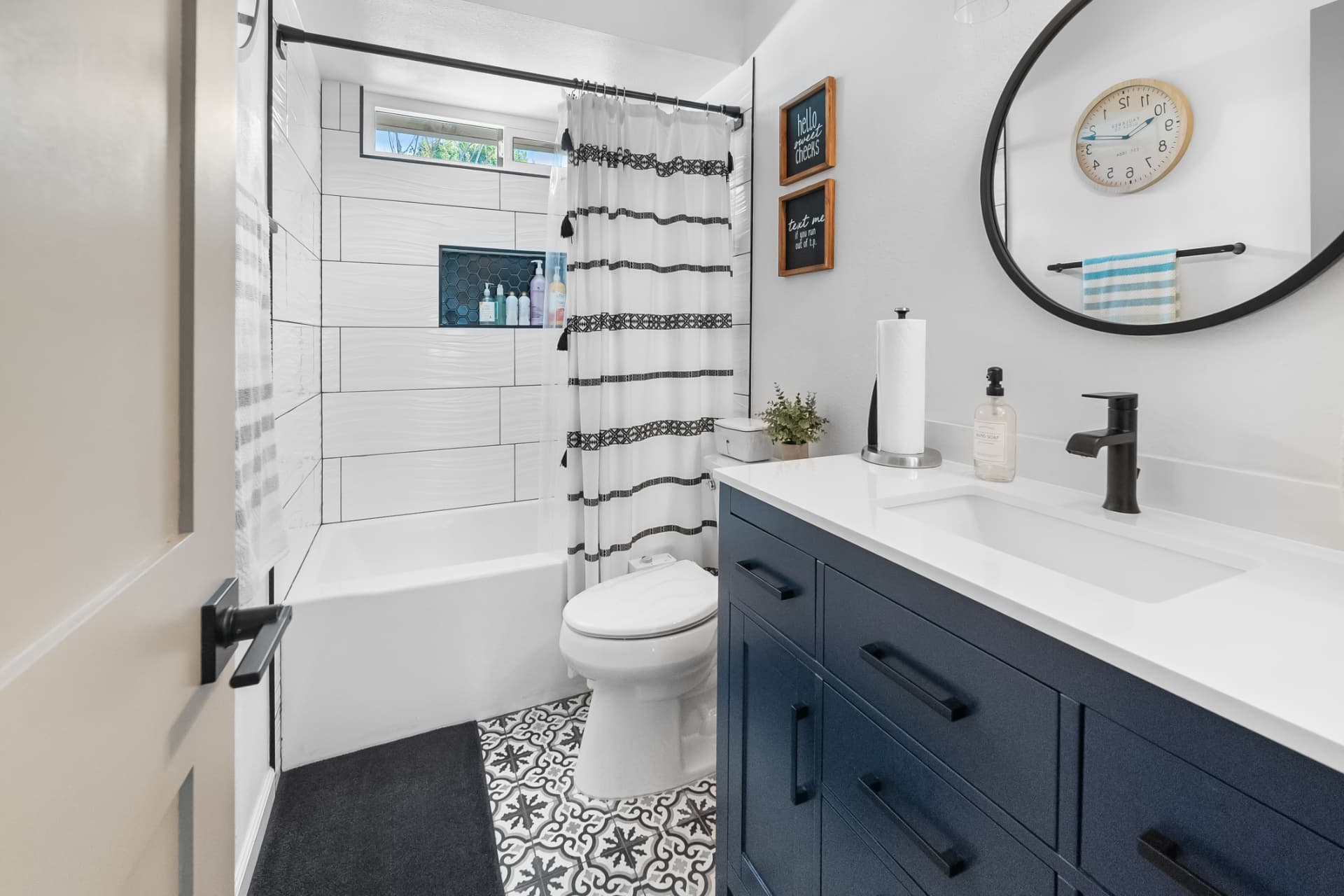 Renovated guest bathroom with navy vanity and patterned tile by Arnold Barrera Construction